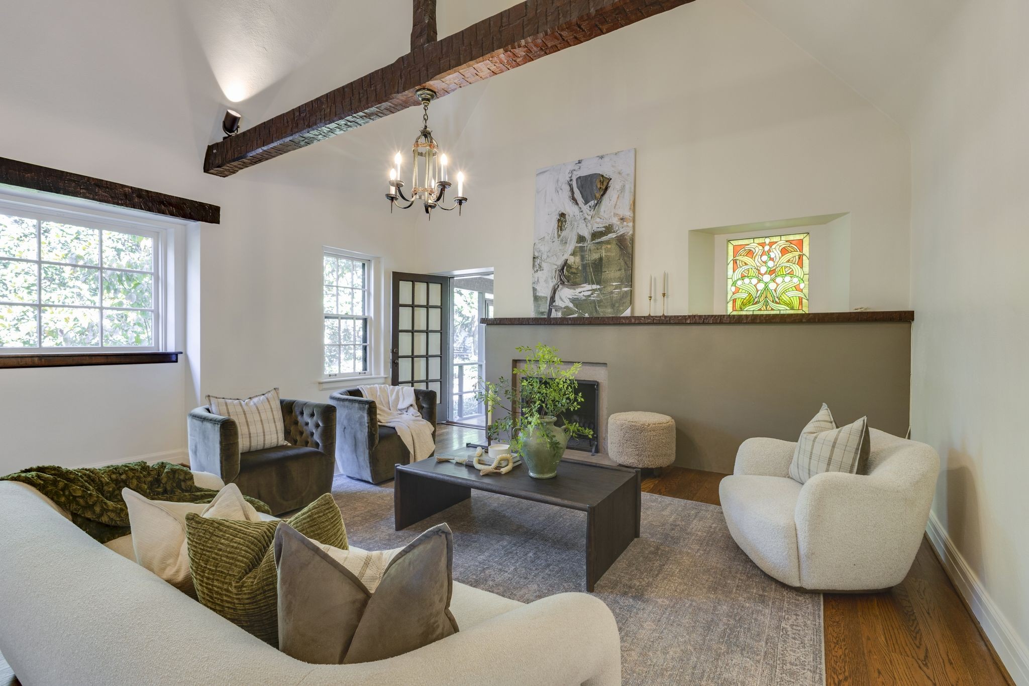 Staged living room with exposed wood beams, fireplace, and seating around a coffee table.