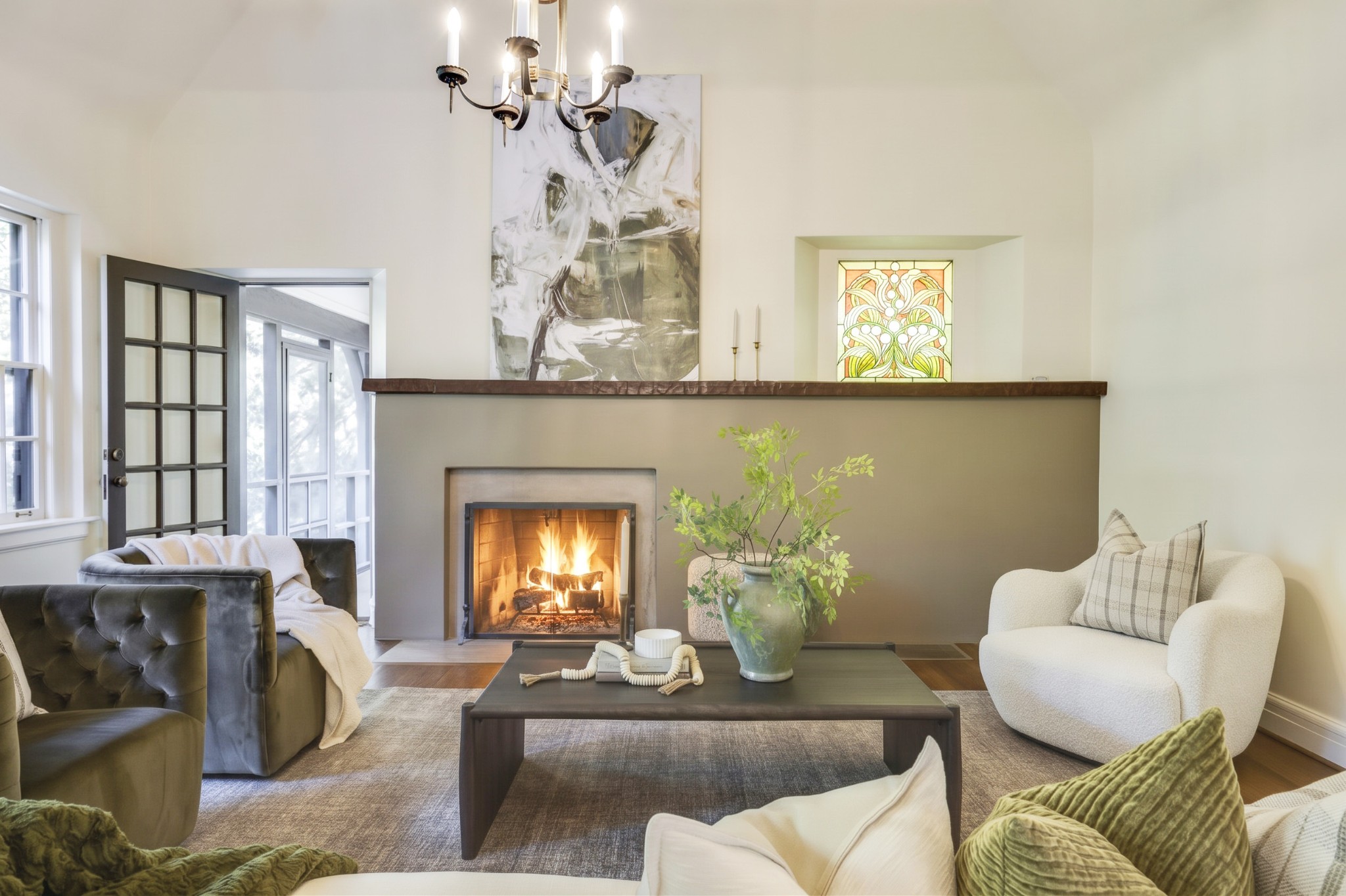 Living room with a lit fireplace, dark mantel, and seating arranged around a coffee table.