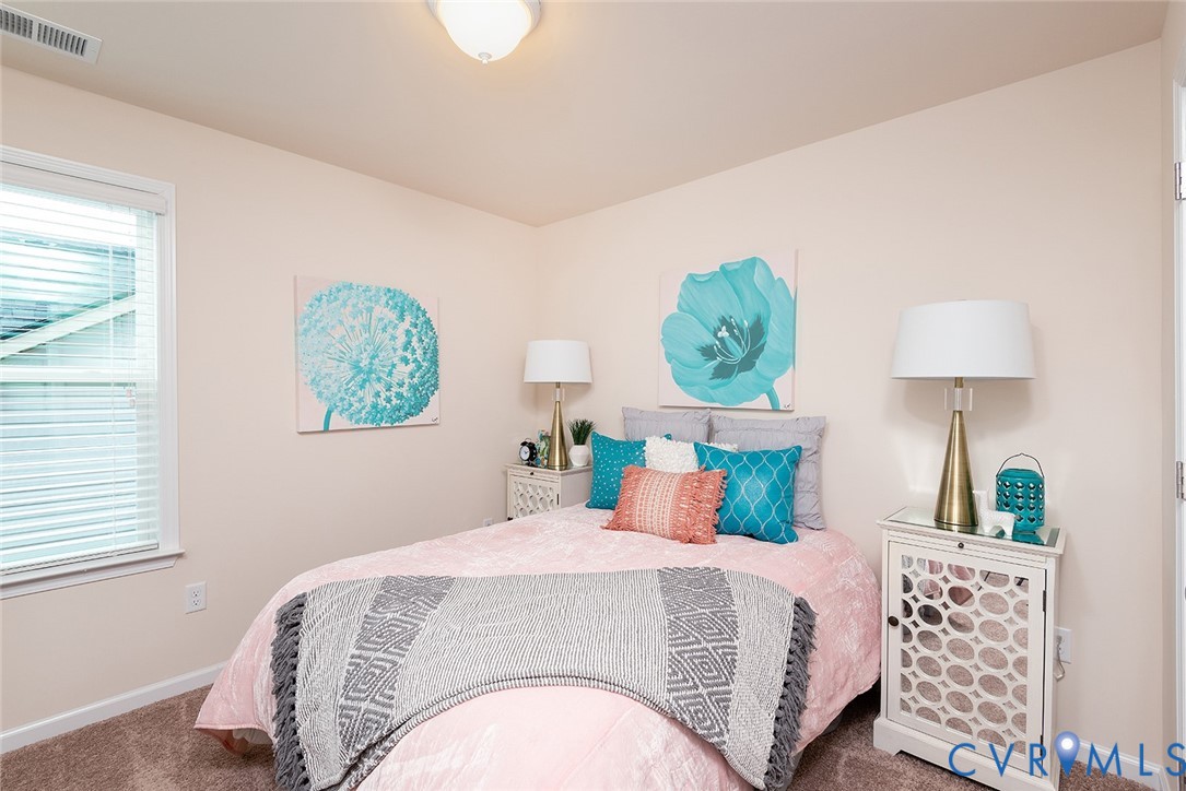 Staged bedroom with pink bedding, turquoise pillows, and floral wall art.