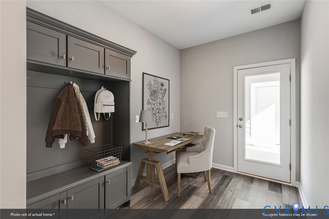 Home office with a wood desk beside dark built-in coat storage and a bench.