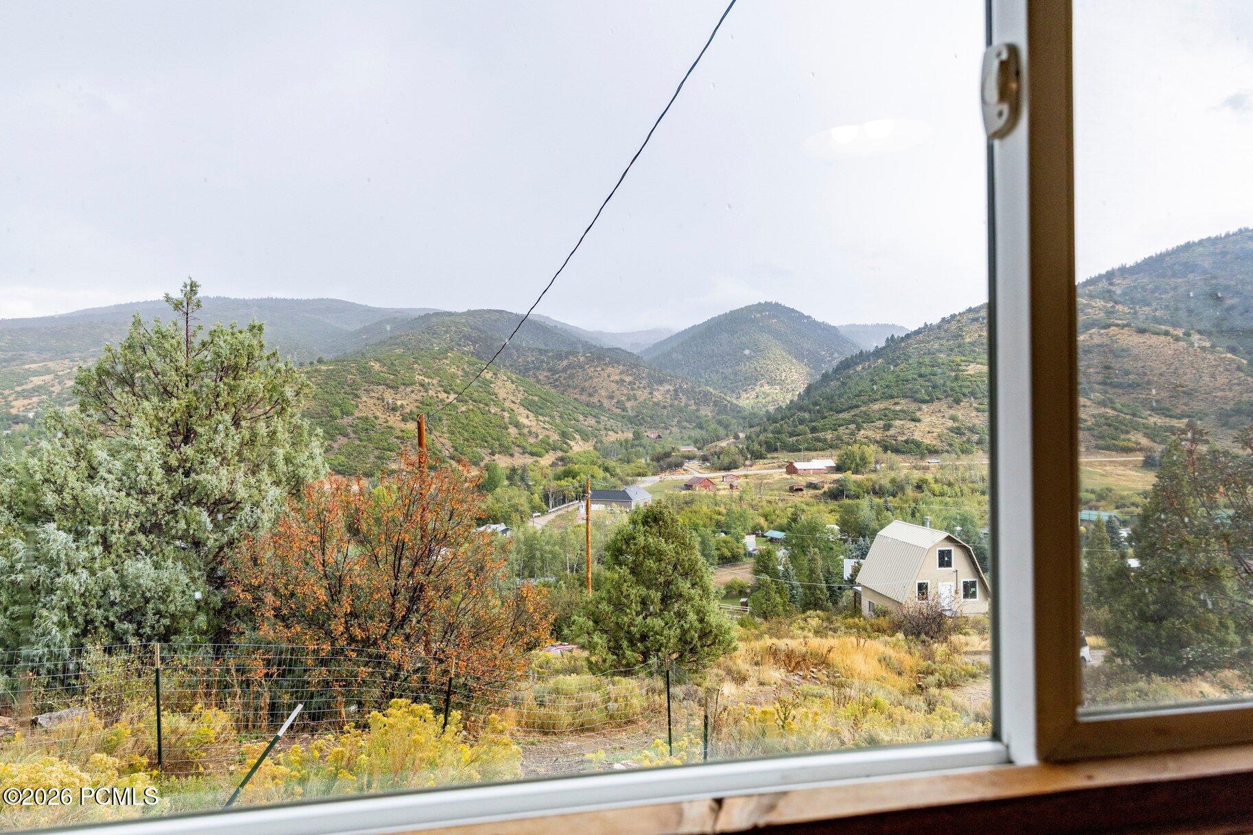 Mountain valley view through a window, with wooded hills, scattered homes, and autumn foliage.