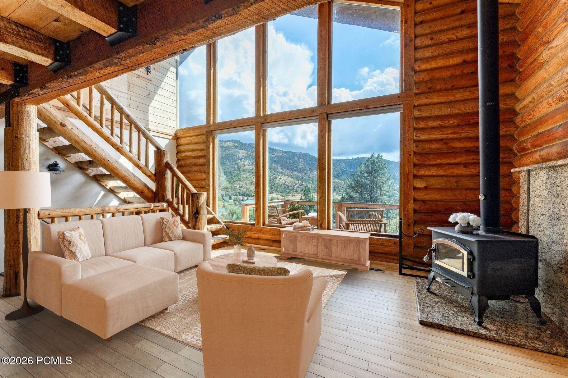 Log-cabin living room with a wood stove and expansive windows overlooking mountains.