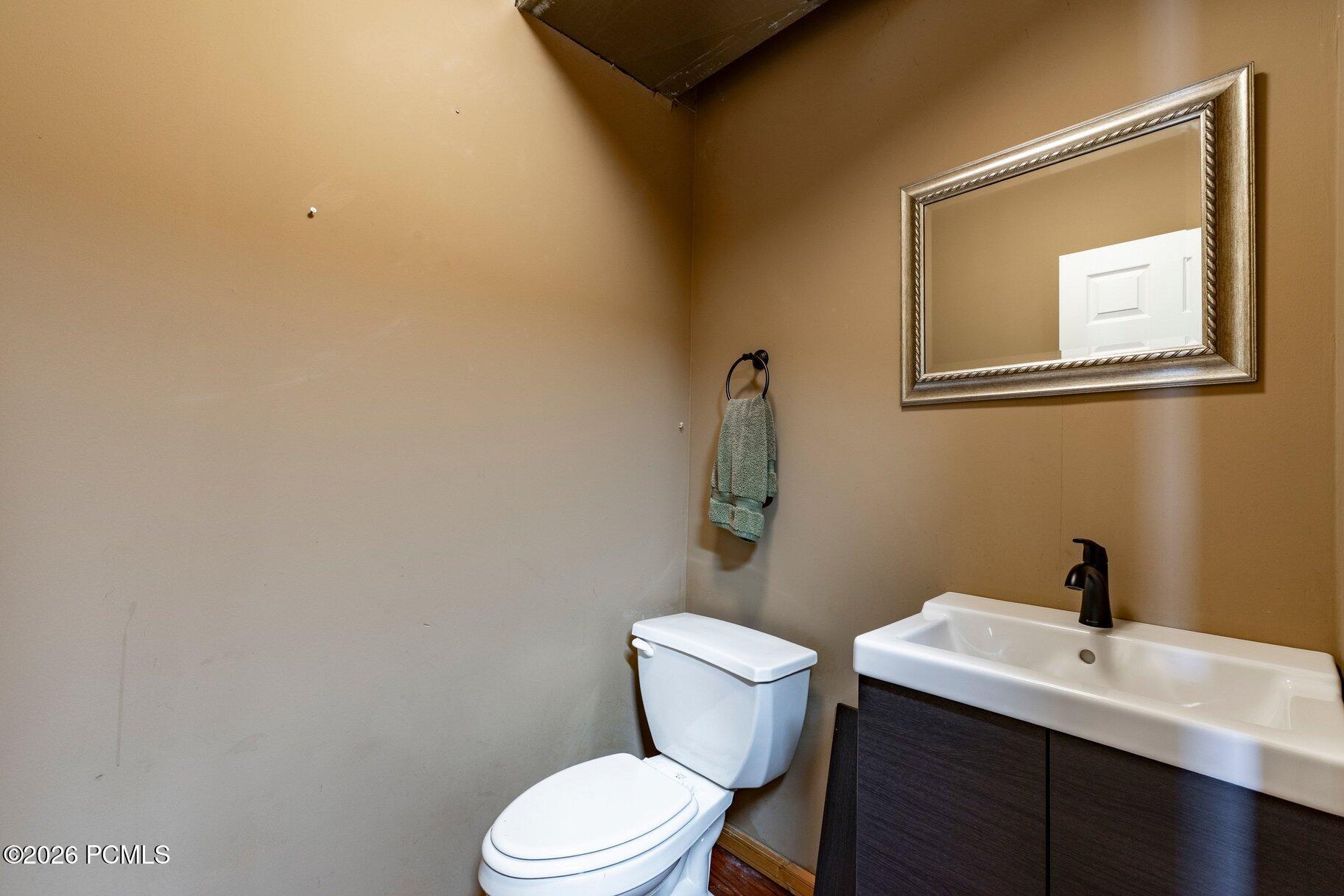 Bathroom with a white toilet, dark wood vanity, and large framed mirror.