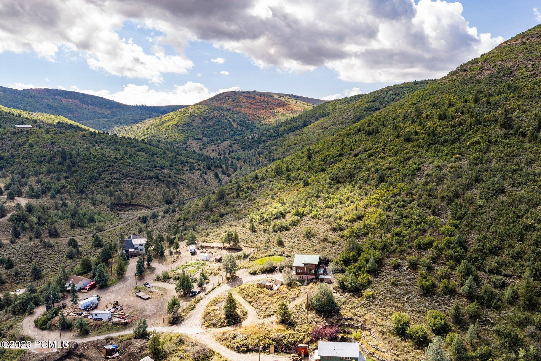 Aerial view of a rural property and scattered buildings surrounded by autumn-colored mountain hills.