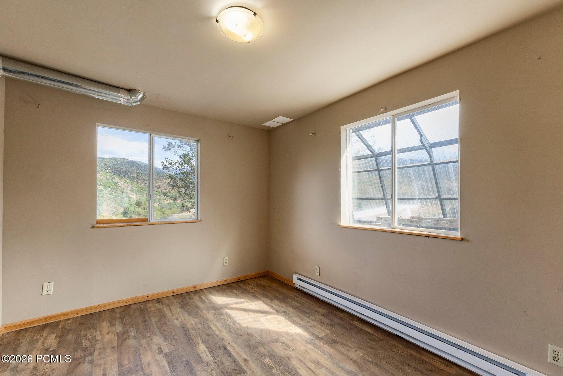Vacant room with wood-look flooring, two windows, and a mountain view.