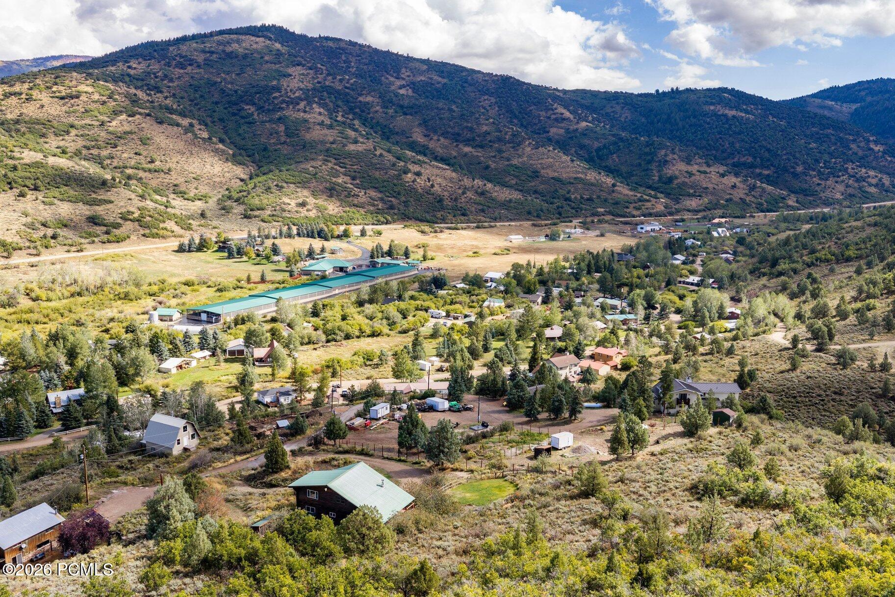 Aerial view of a rural valley neighborhood beneath wooded mountains.