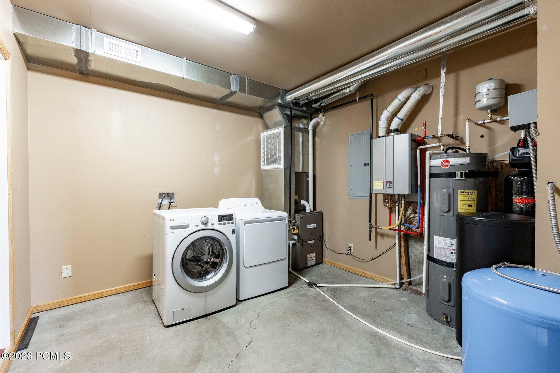 Utility room with a washer and dryer beside HVAC equipment and water heaters.