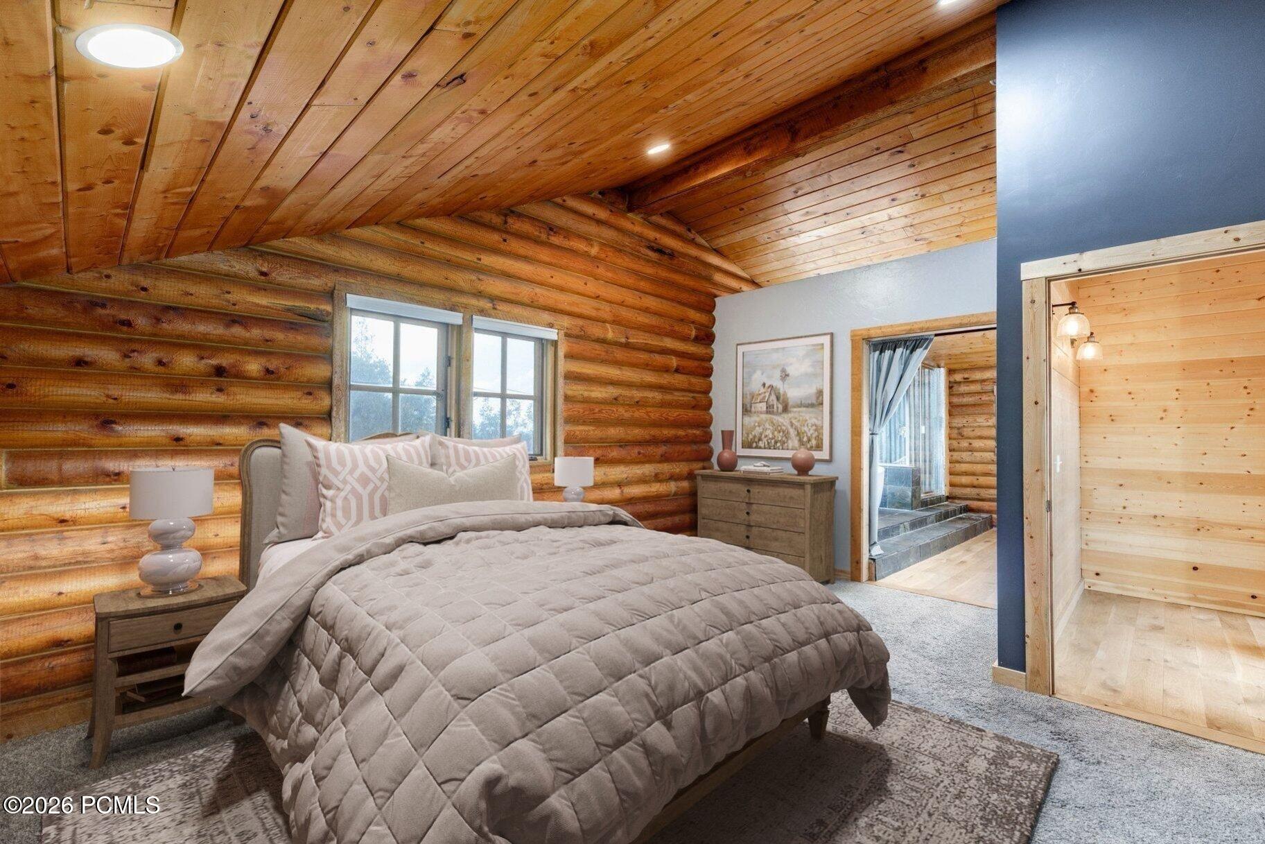 Bedroom with a quilted bed, log walls, and a vaulted wood ceiling.