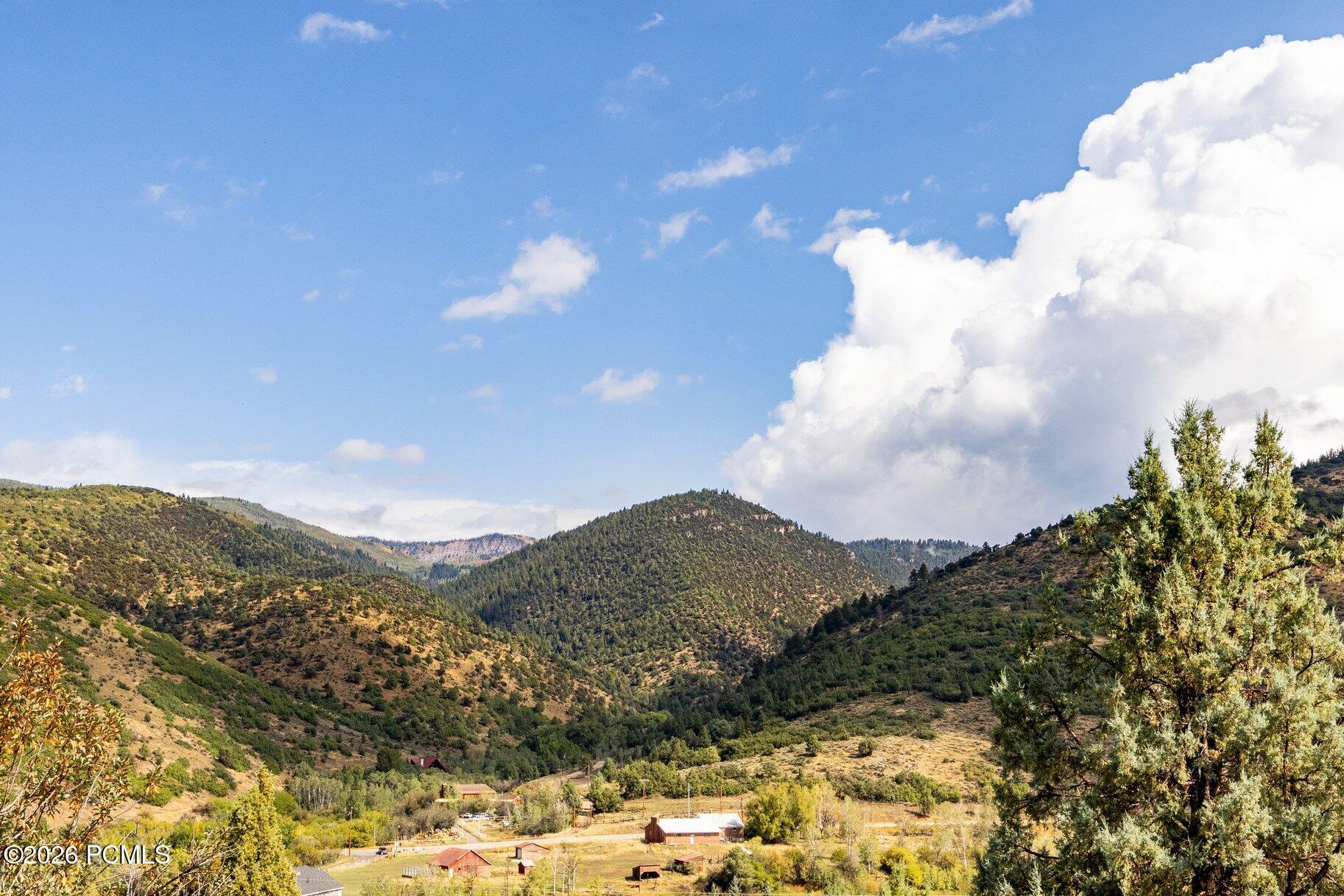 Panoramic view of wooded mountain ridges and a rural valley beneath large clouds.