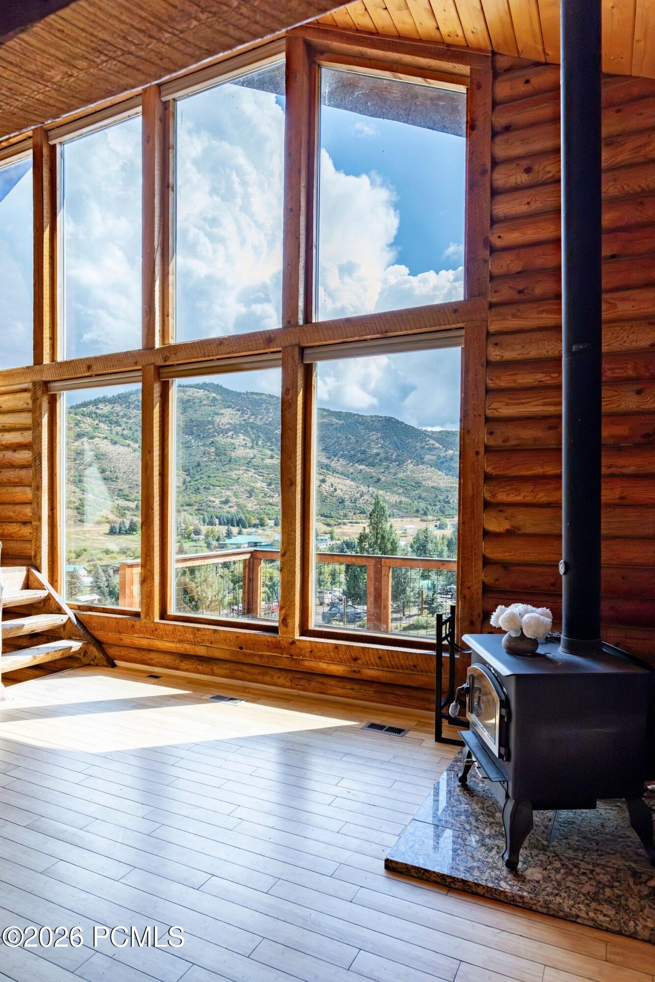 Rustic living room with a wood-burning stove and expansive windows framing a mountain view.