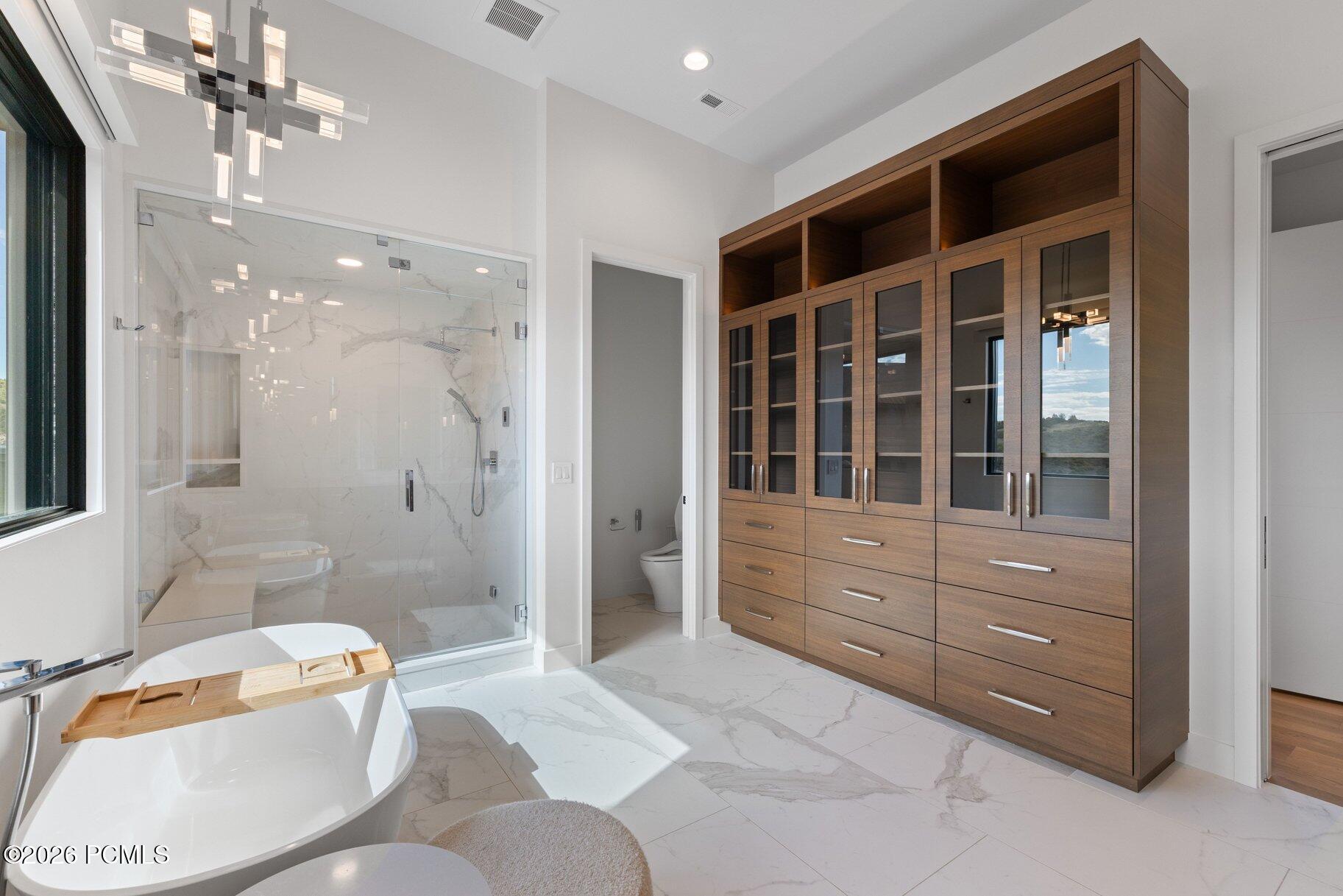 Modern bathroom with a freestanding tub, marble shower, and walnut vanity.