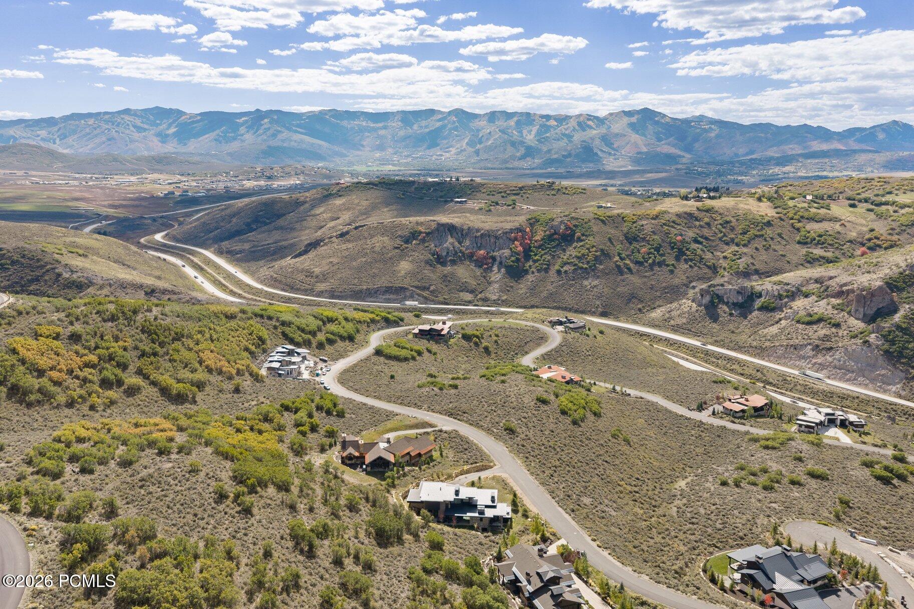Aerial view of hillside homes and winding roads with mountains in the distance.