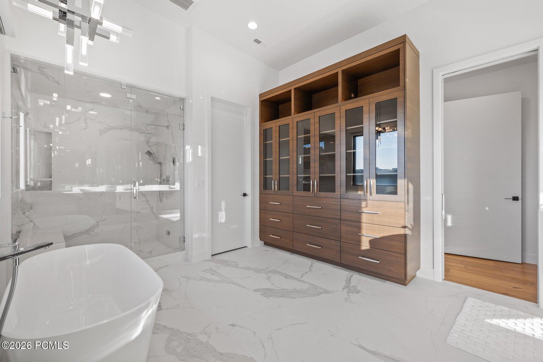 Modern bathroom with a freestanding tub, marble shower, and dark wood cabinetry.