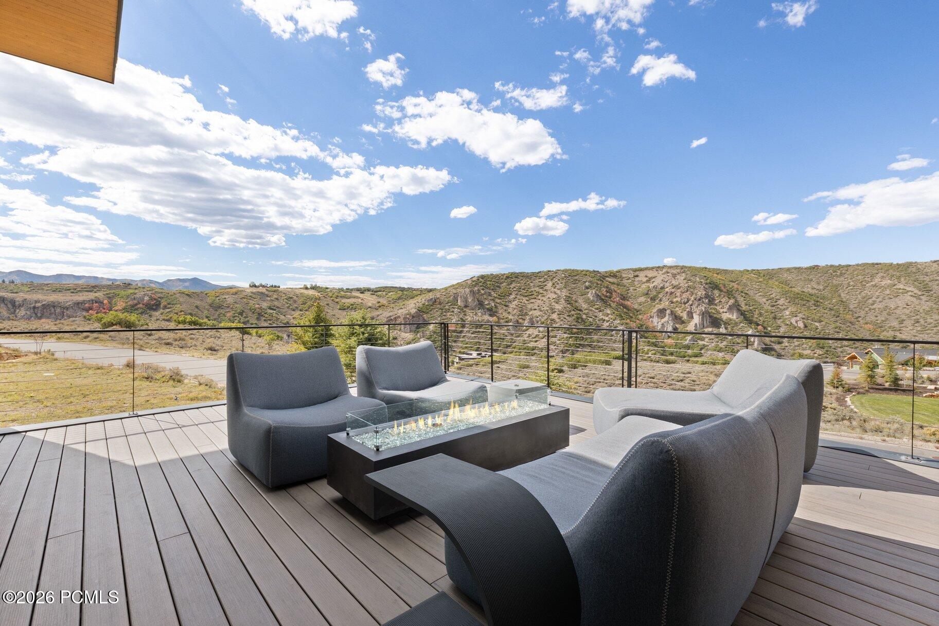 Deck seating and gas fire table overlooking rocky hills and distant mountains.