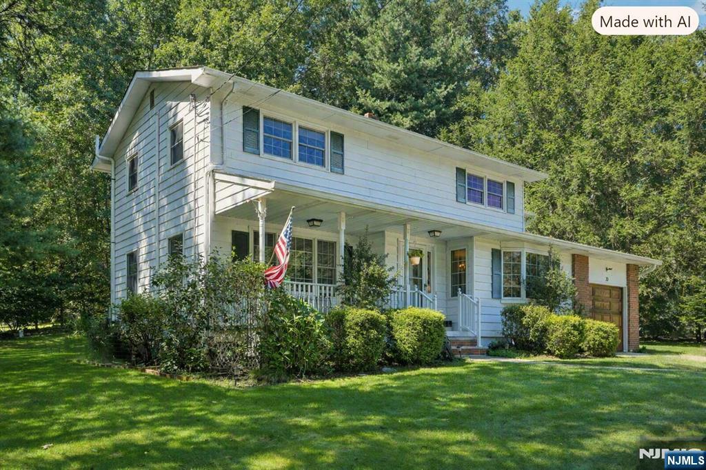 Two-story white house with blue shutters, a covered porch, and an American flag amid mature trees.