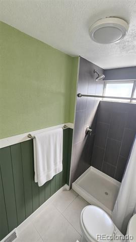 Bathroom with a dark tiled shower, white shower base, green walls, and towel bar.