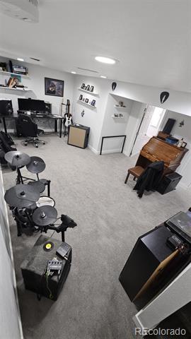 Carpeted music room with a drum kit, keyboard, and piano.