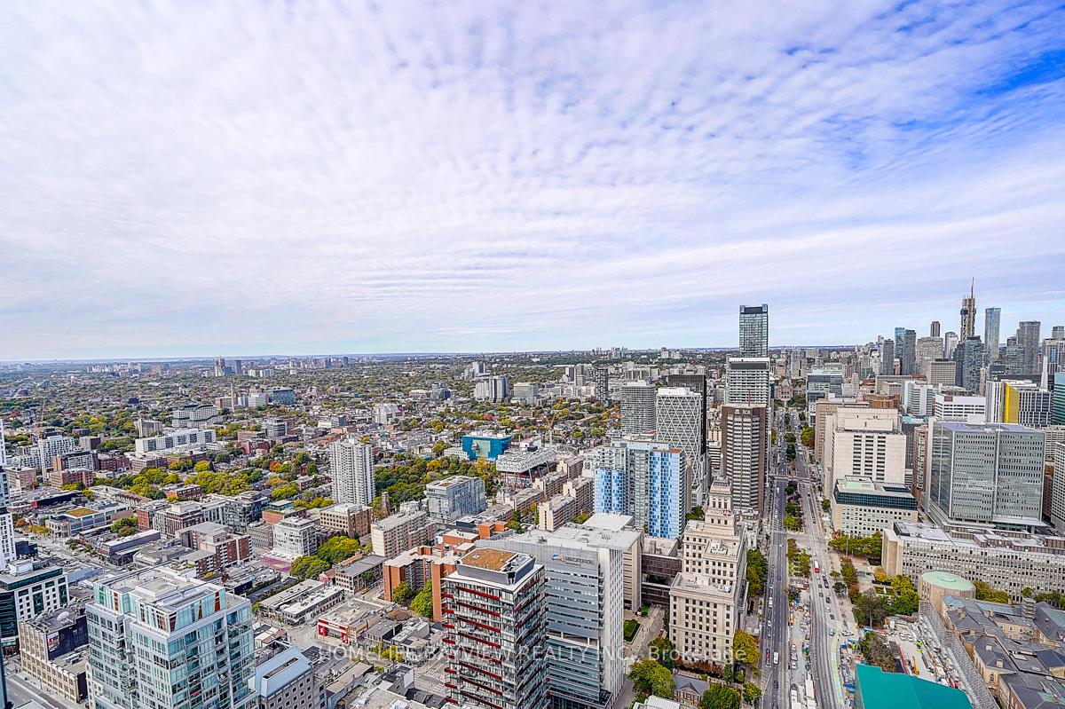 Panoramic Toronto skyline with the CN Tower and dense cityscape beneath a cloud-streaked sky.