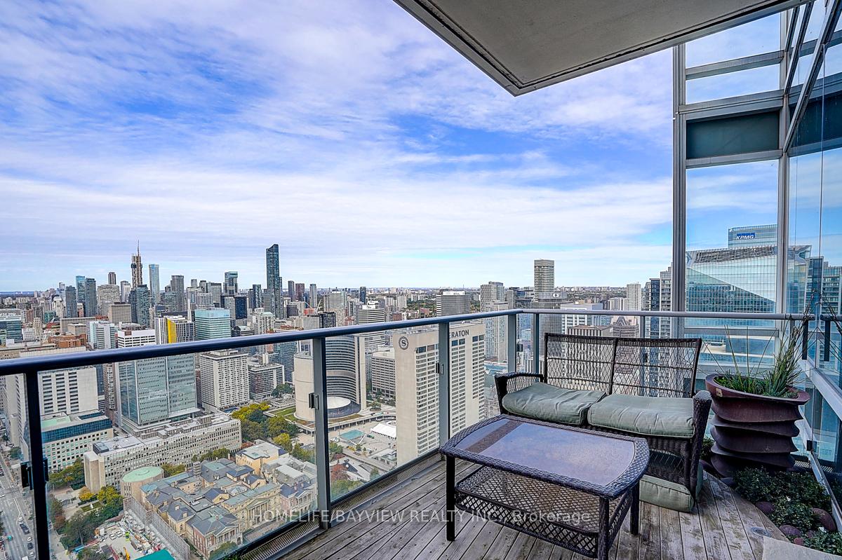 Penthouse balcony with wicker seating and a panoramic view of the Toronto skyline.