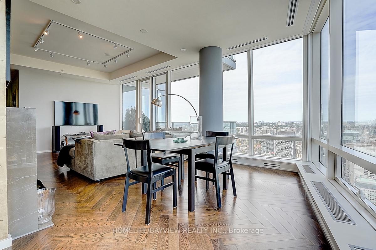 Condo living and dining area with floor-to-ceiling windows overlooking the city.