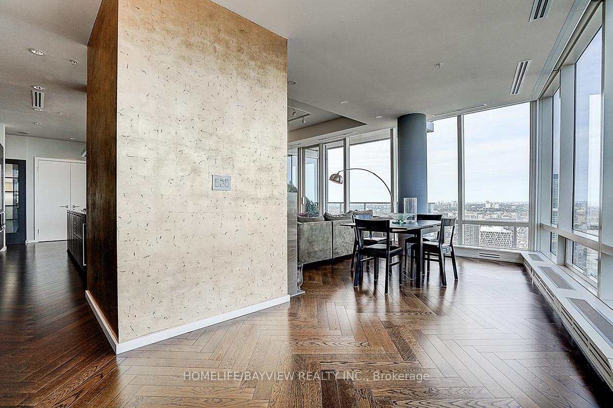 Dining and living area with floor-to-ceiling windows, parquet floors, and a city view.