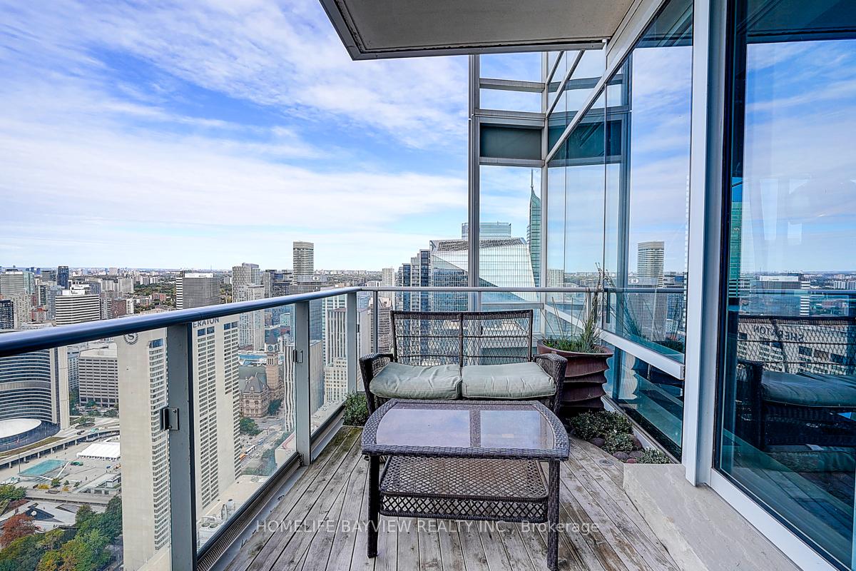 Penthouse balcony with outdoor seating and planters overlooking downtown Toronto.