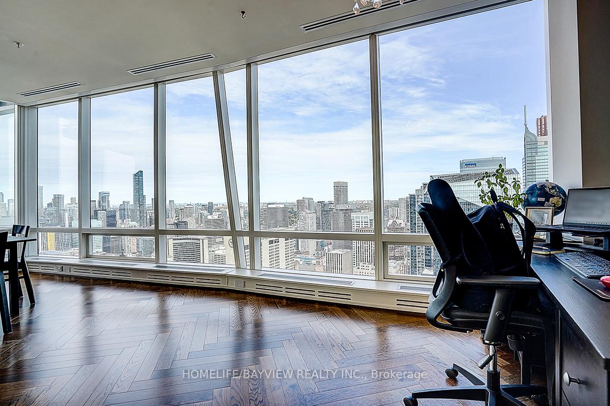 Condo office with hardwood floors, a desk, and floor-to-ceiling windows overlooking the downtown skyline.