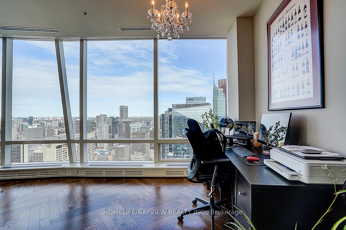 Home office with a dark desk and floor-to-ceiling windows overlooking Toronto’s skyline.