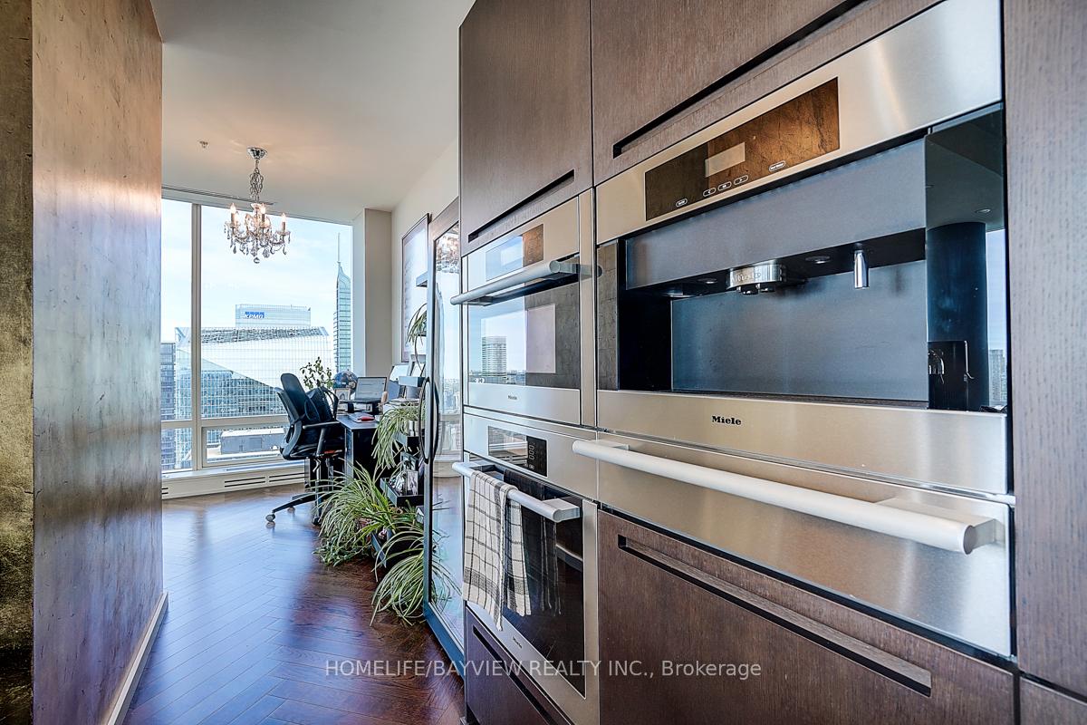 Condo kitchen with built-in stainless steel appliances, opening to a desk nook and city views.