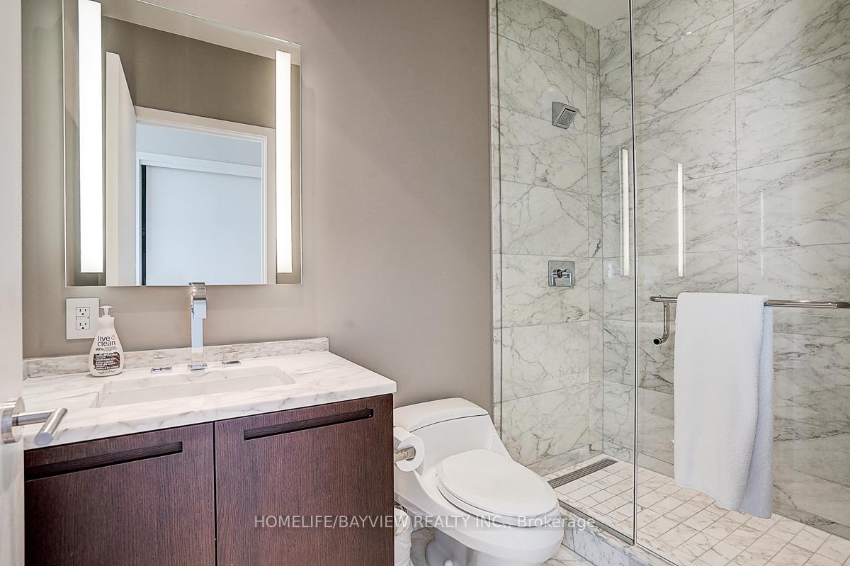 Bathroom with a dark wood vanity and a glass-enclosed marble shower.