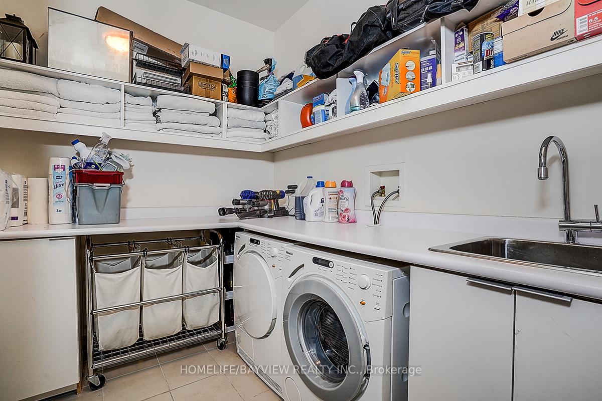 Laundry room with front-loading washer and dryer, utility sink, and extensive overhead storage.