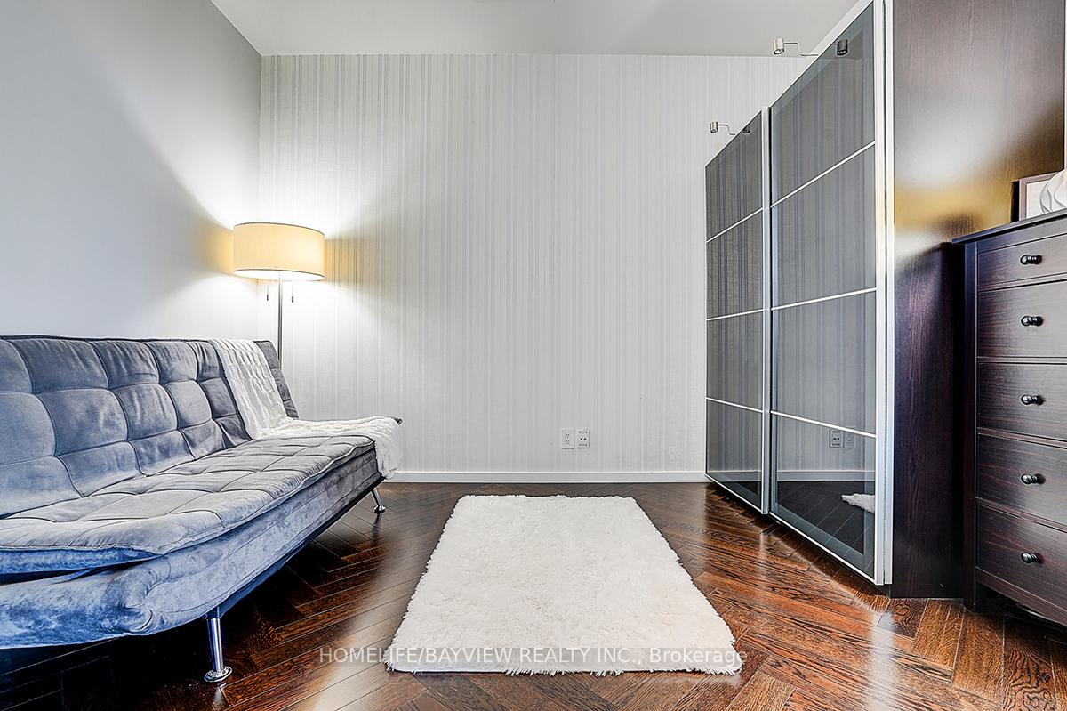 Furnished room with a blue tufted sofa, mirrored wardrobe, and dark wood flooring.