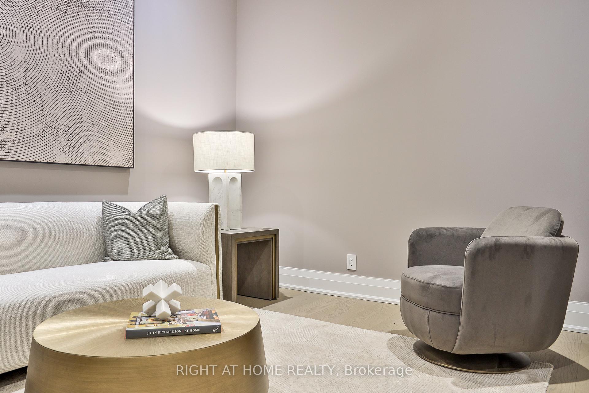 Staged living room with a cream sofa, gray swivel chair, and round wood coffee table.