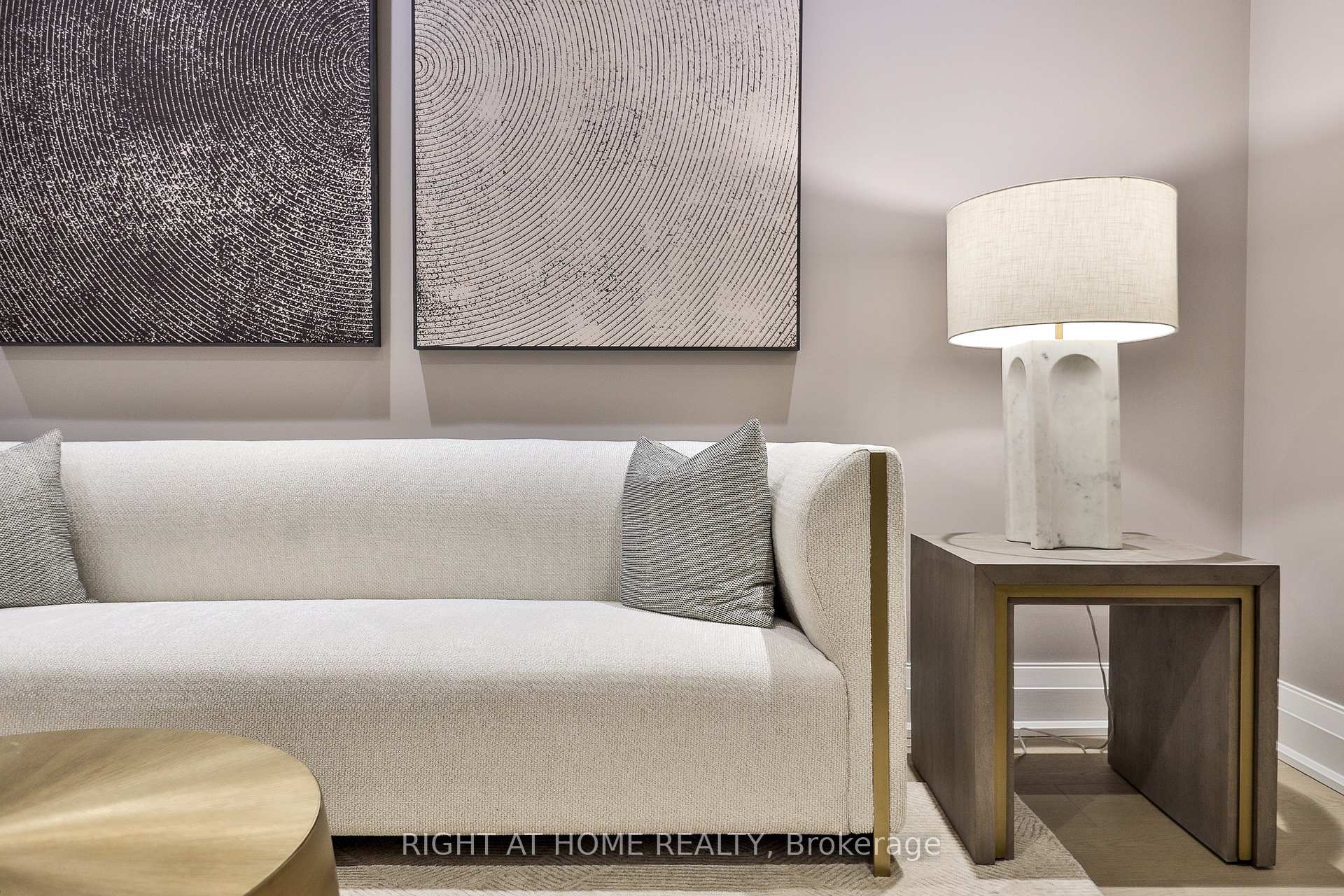 Living room with a light sofa, abstract wall art, and a marble-base table lamp.