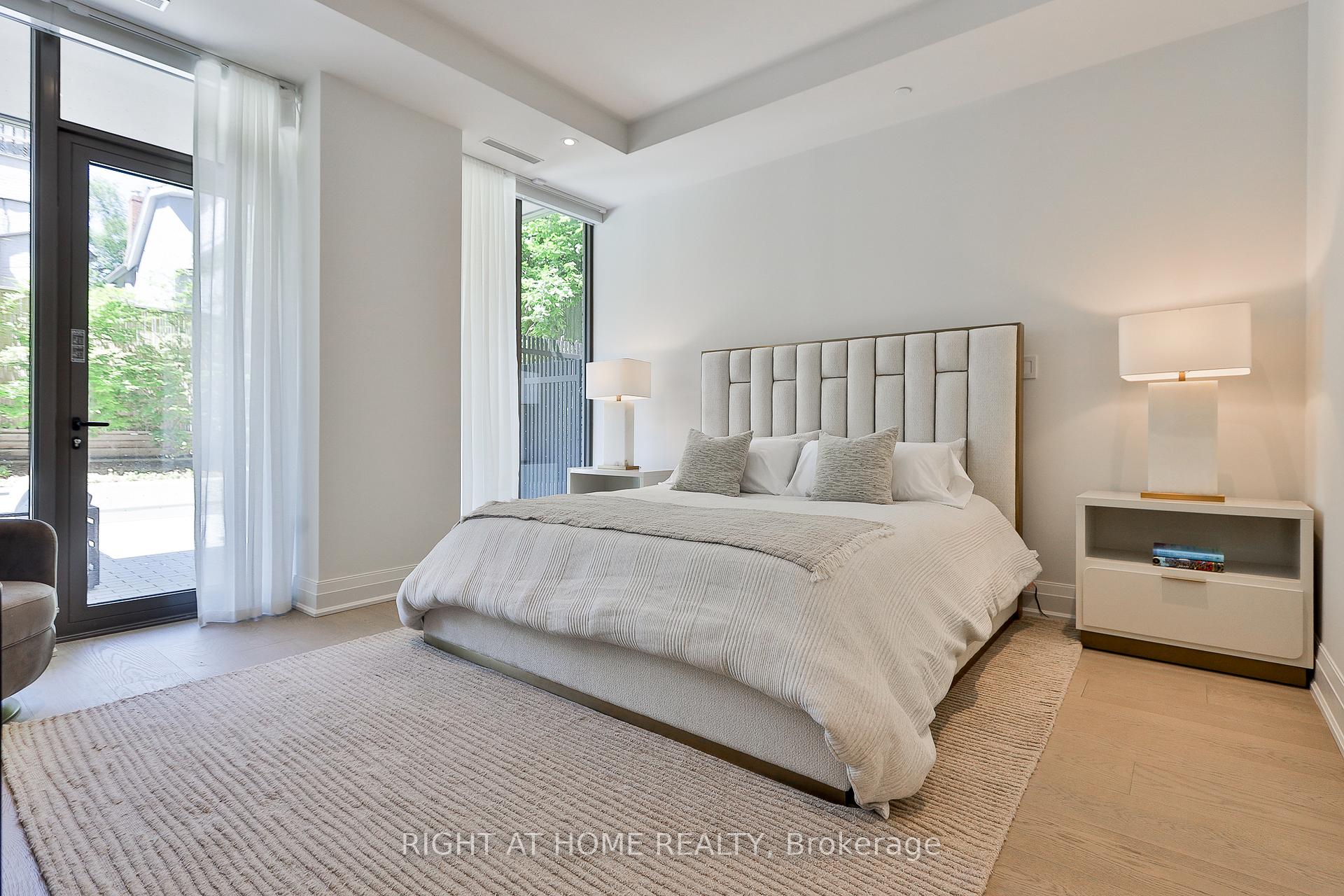 Bright bedroom with a large upholstered bed and glass doors opening onto a garden patio.