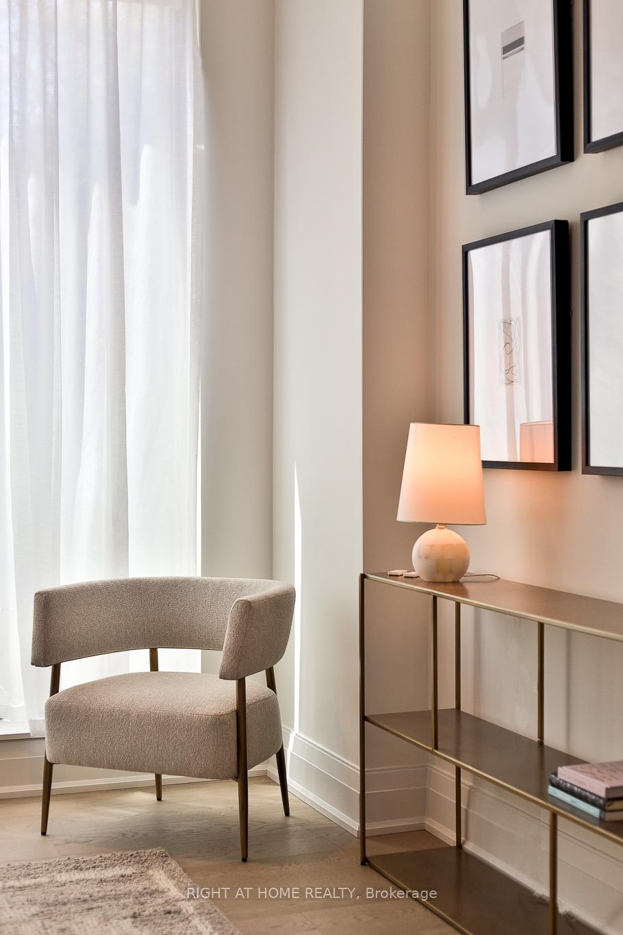 Upholstered accent chair beside a console table with a lit lamp and framed artwork.