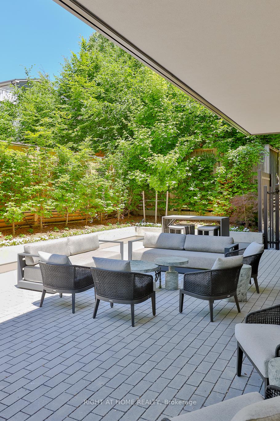Covered patio with contemporary lounge seating and a leafy garden.