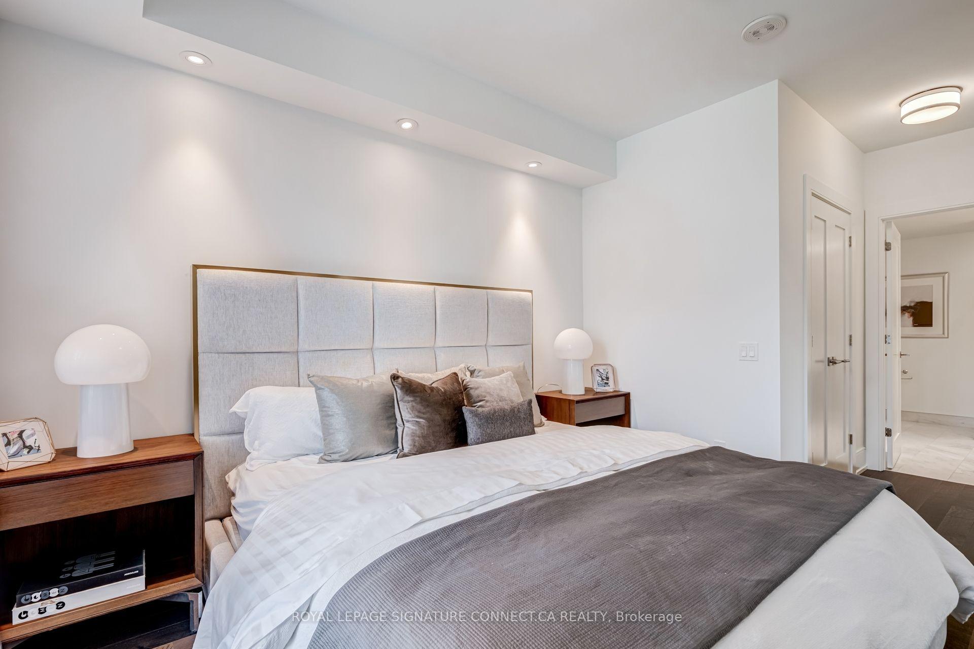 Bedroom with an upholstered headboard, white bedding, gray throw, and matching wood nightstands.