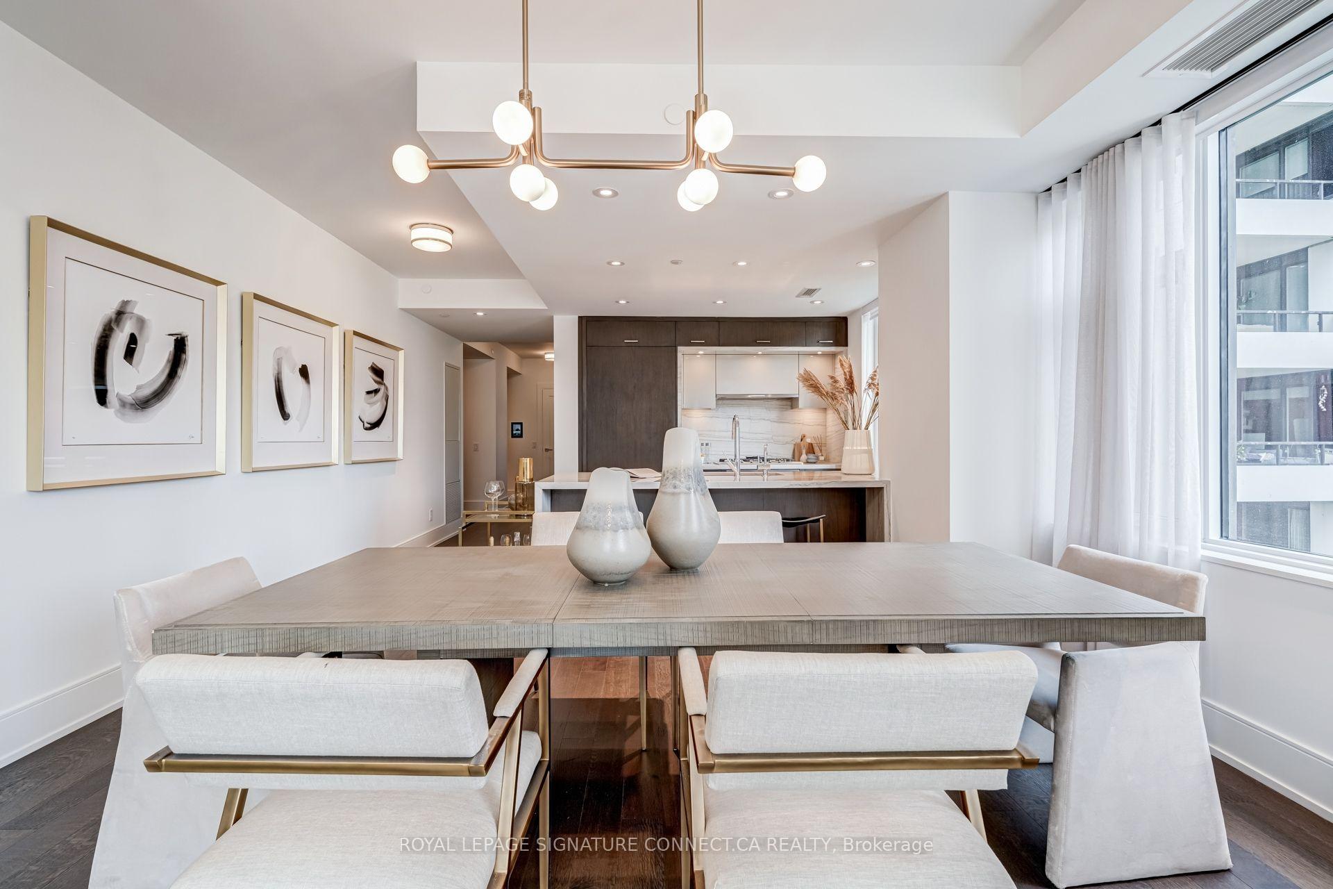 Furnished condo dining area with a large table, abstract wall art, and an open modern kitchen.