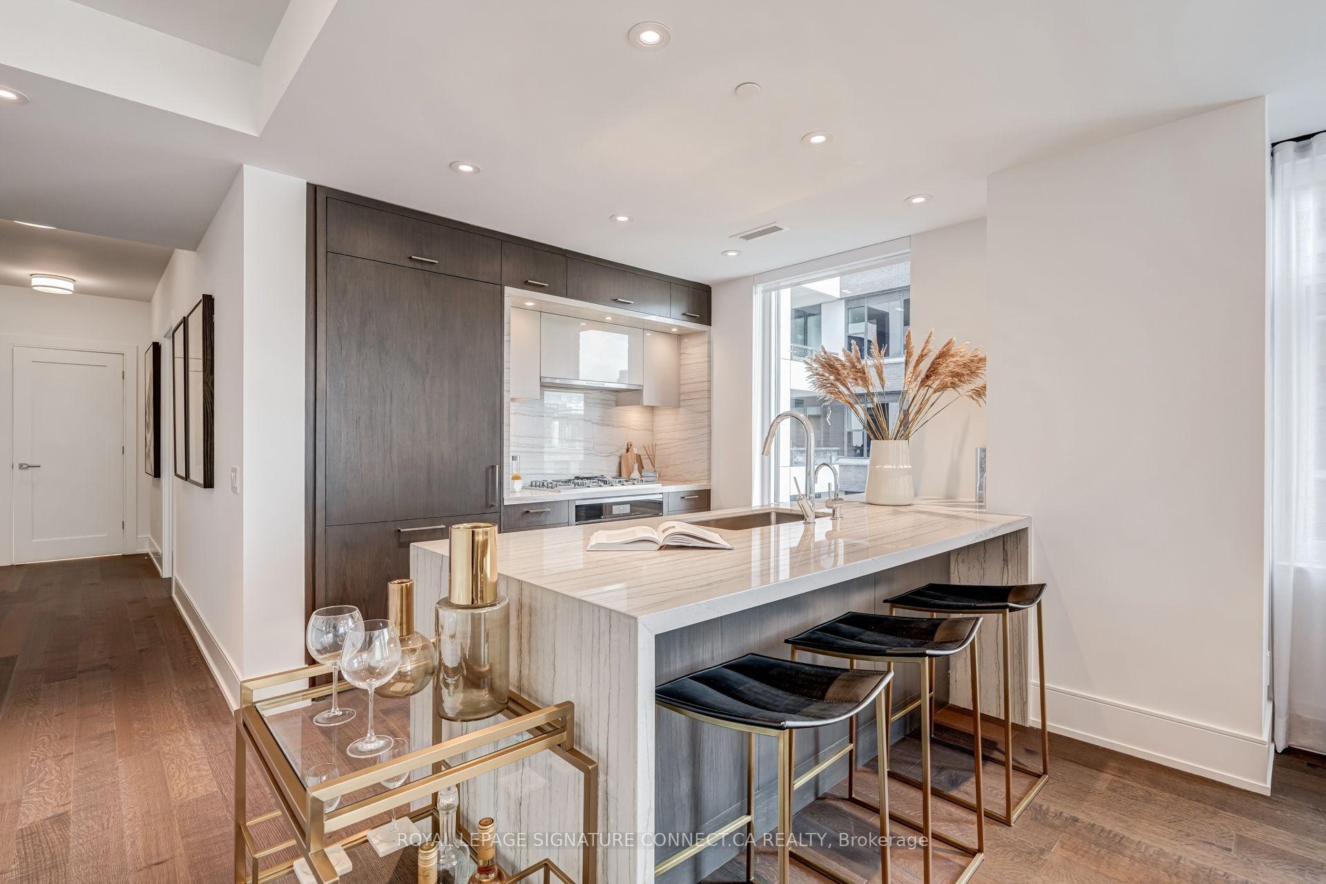 Modern condo kitchen with a veined stone island, dark cabinetry, and black bar stools.