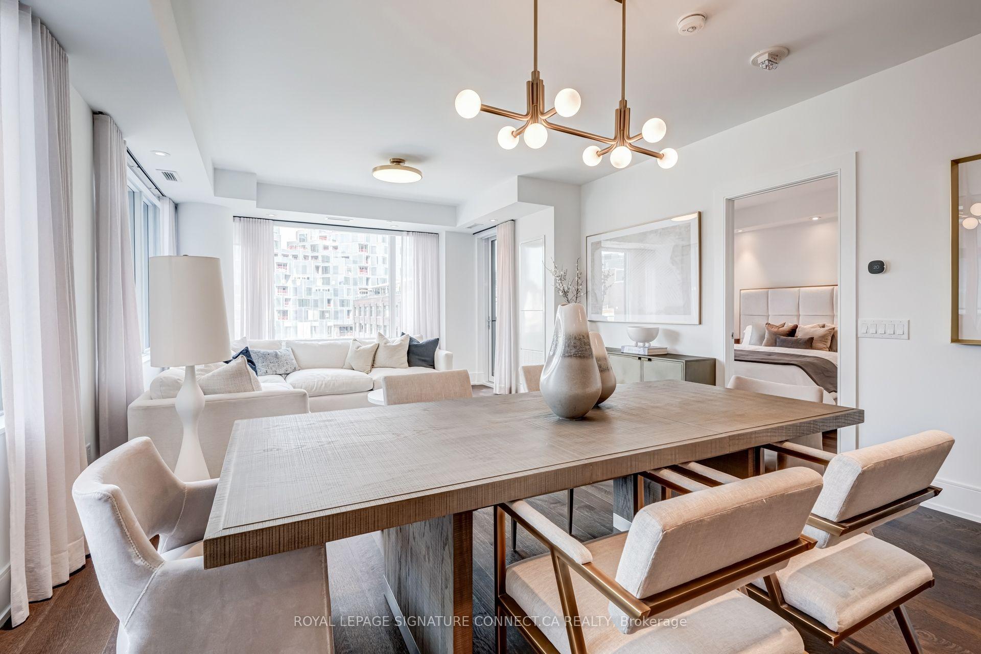 Condo dining and living area with a large wood table, contemporary lights, and tall windows.