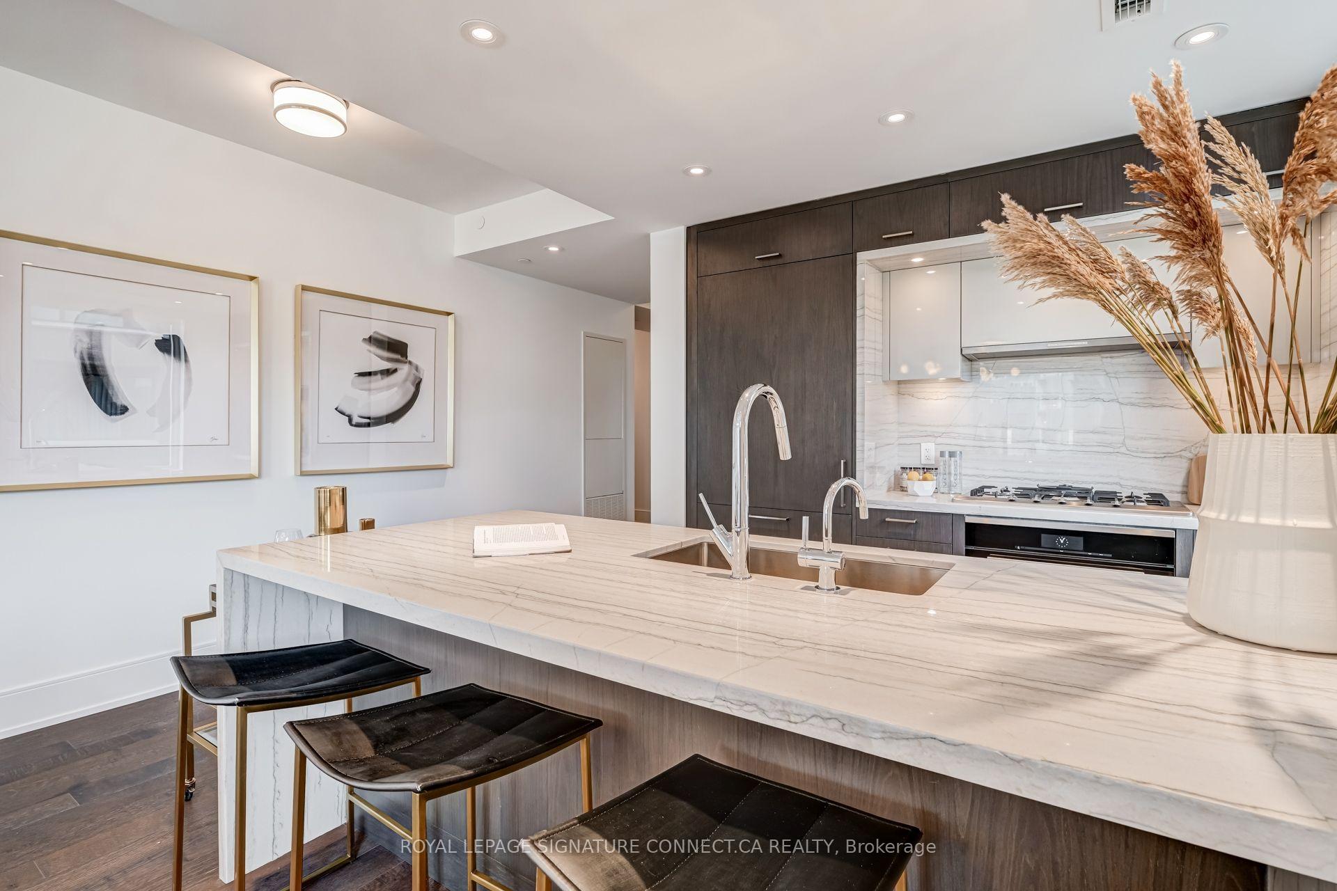 Modern condo kitchen with a veined marble island, dark cabinetry, and black bar stools.