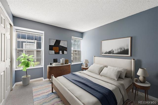 Staged bedroom with a white bed, navy throw, blue-gray walls, and two windows.