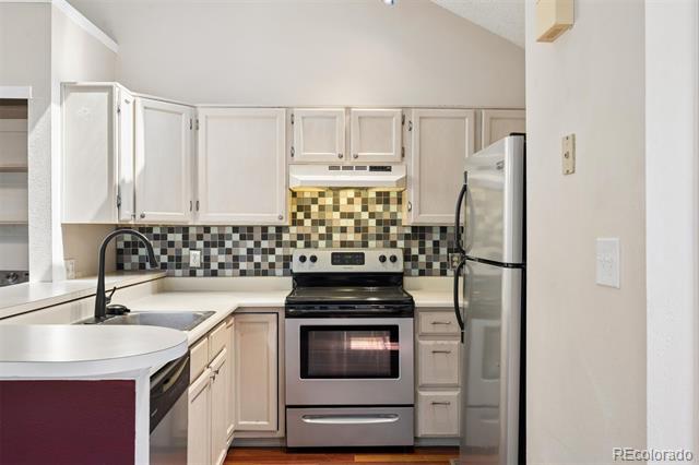 Kitchen with white cabinets, checkerboard tile backsplash, and stainless steel appliances.