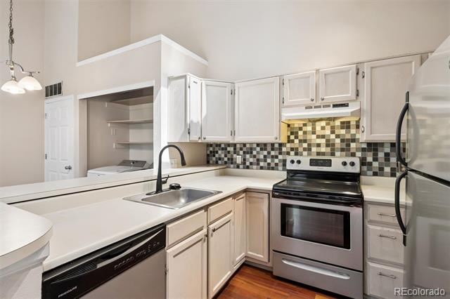 Kitchen with white cabinets, a multicolored tile backsplash, and a peninsula sink.