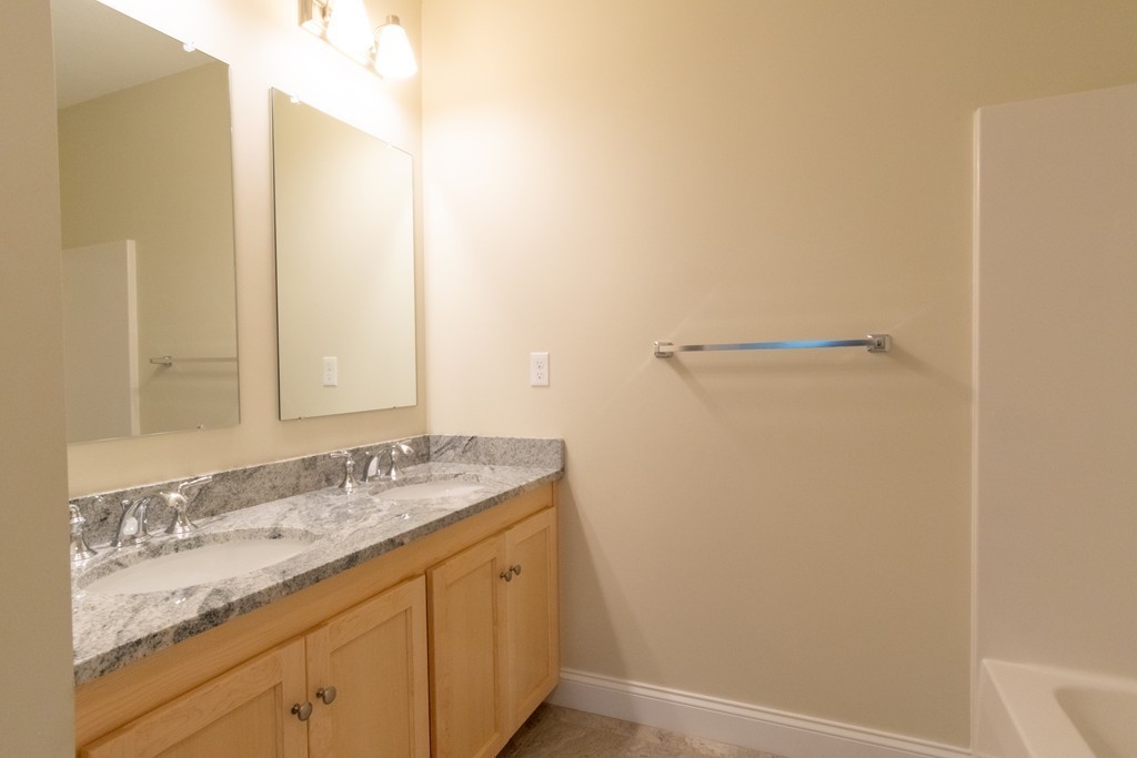 Bathroom vanity with double sinks, granite countertop, oak cabinets, and wall mirrors.