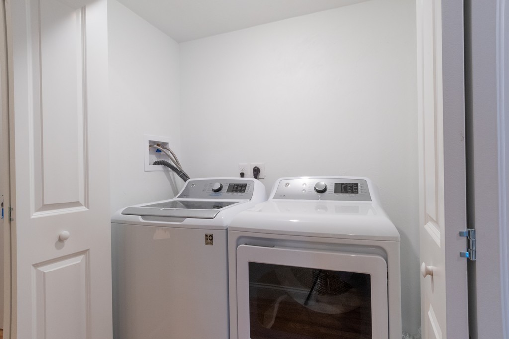 Laundry room with a top-load washer and front-load dryer behind open closet doors.