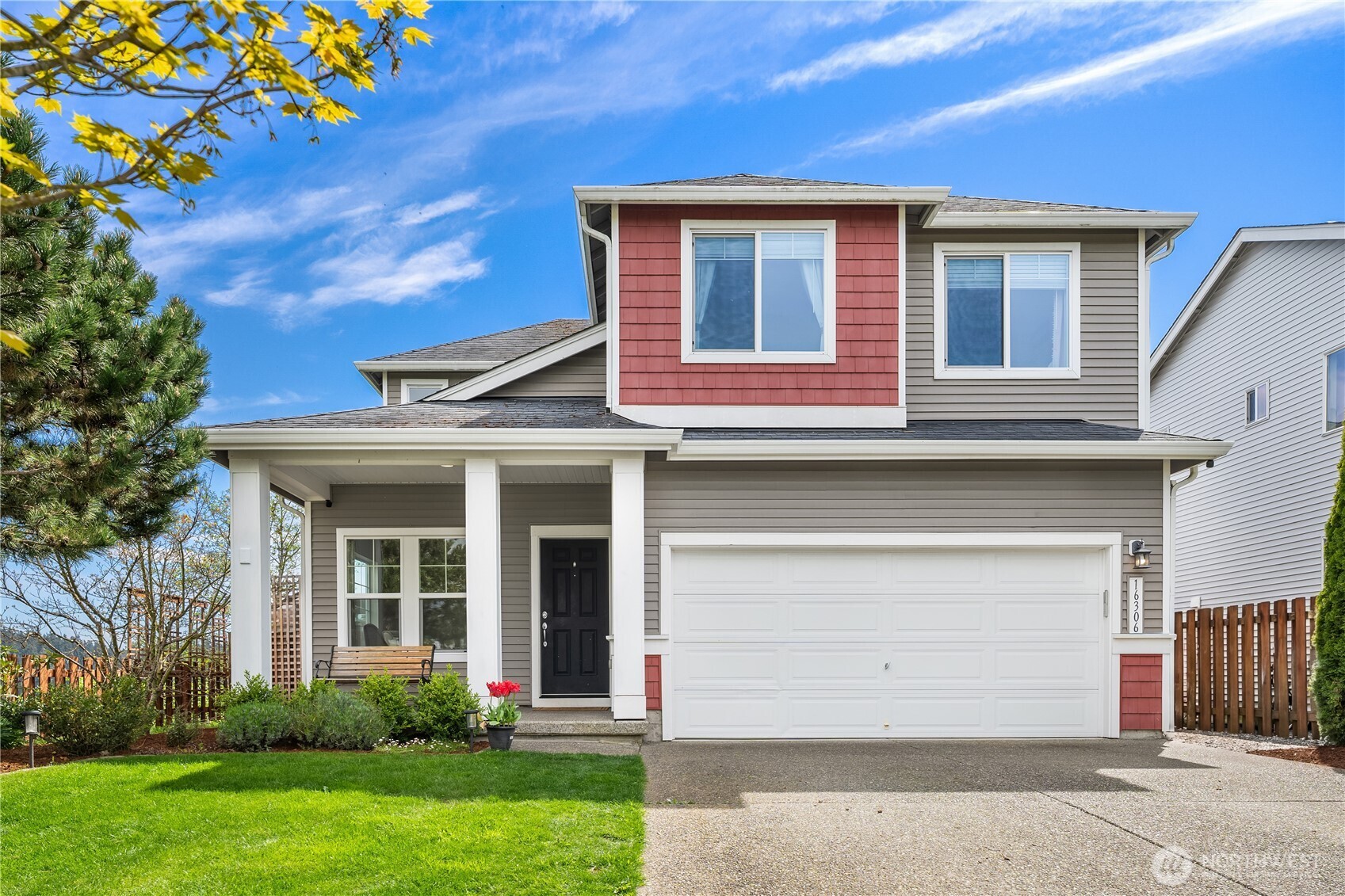 Two-story gray house with red accents, a covered porch, and a white double garage door.