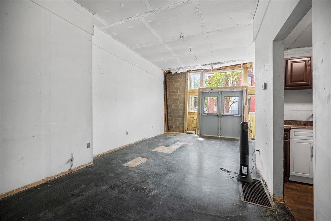 Unfinished interior room with a glazed entrance, exposed masonry, and part of a kitchen visible.