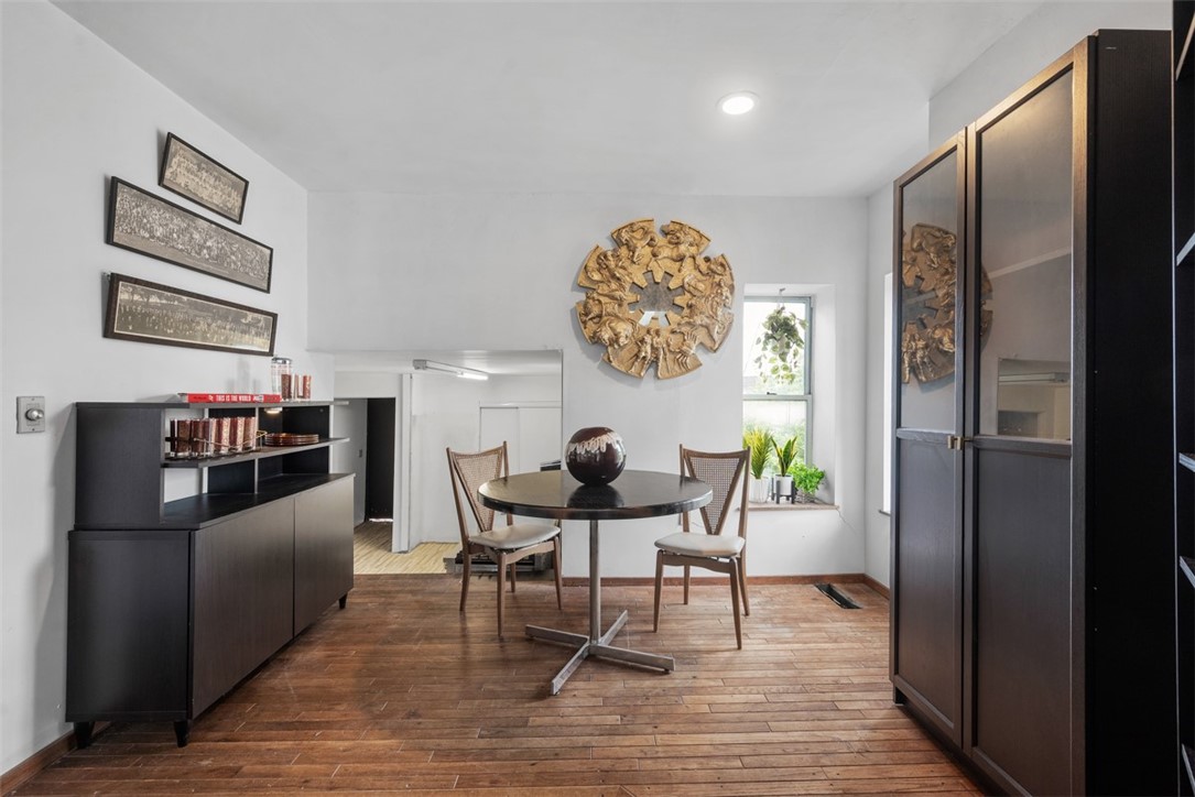 Dining area with a round table, two chairs, dark cabinetry, and hardwood floors.